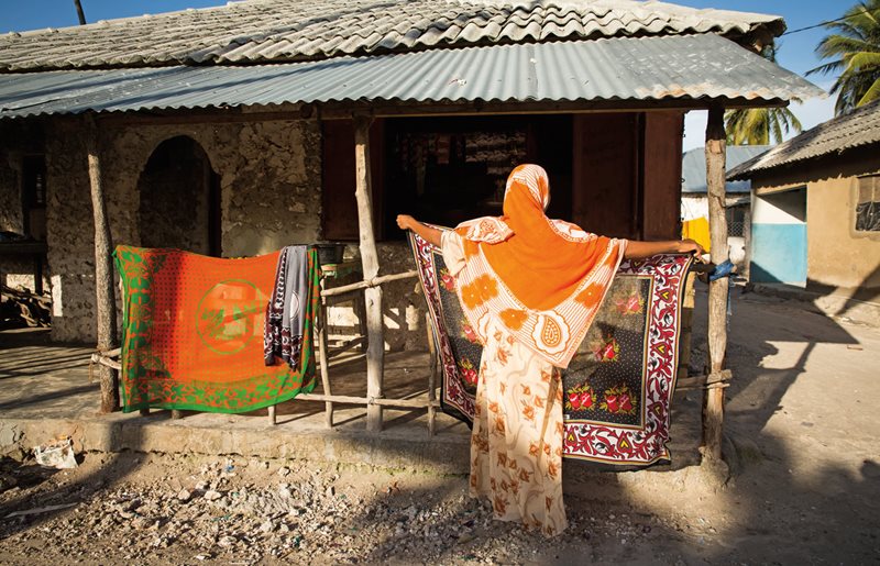 Жительница Бведжуу развешивает канги сушиться на утреннем солнце