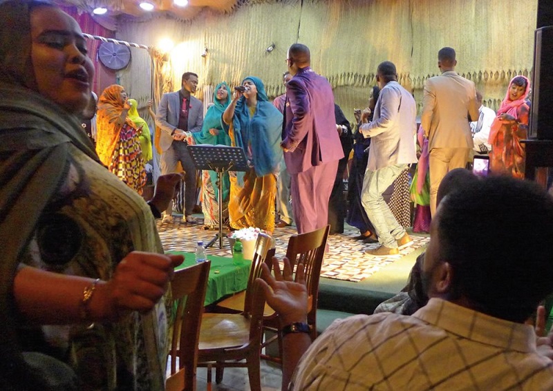 Певица Сахра Халган (в центре) построила ресторан и клуб «Хиддо заур», что значит «спасите свою культуру». Здесь выступает она сама и другие исполнители. Нередко во время выступлений публика поднимается на сцену и начинает танцевать рядом с музыкантами, и даже фотографируется с ними. «Во время войны я была медсестрой Сомалийского национального движения… Мы пели тяжело раненым и умирающим», — рассказывает Халган
