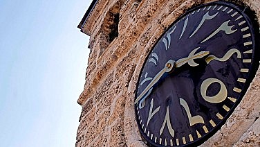 Вид вблизи на циферблат османских часов, на котором до сих пор сохранились арабские цифры, указывающие на время начала намаза