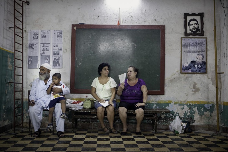 Сидя под портретами Че Гевары и Фиделя Кастро, Мухаммад Али с внуком Дарио дожидаются тренировки по джиу-джитсу в спортивном зале в историческом центре Гаваны – одном из самых густонаселенных районов города