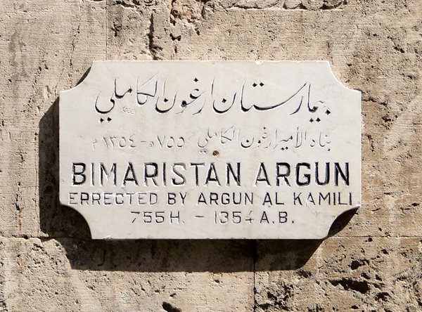 Табличка на стене бимаристана Аргун в Алеппо, Сирия, в честь основателя, эмира Аргуна аль-Камили (середина XIV в.). Здесь душевнобольных лечили дневным светом, свежим воздухом, водными процедурами и музыкой