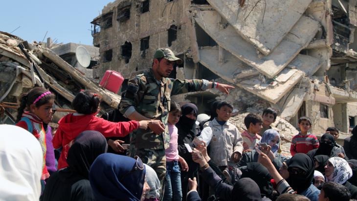 Жители лагеря палестинских беженцев Ярмук предъявляют документы военнослужащему, чтобы покинуть опасную зону.