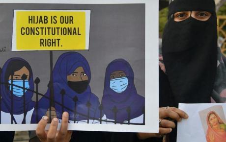 Мусульманка держит плакат с надписью «Хиджаб — наше конституционное право».